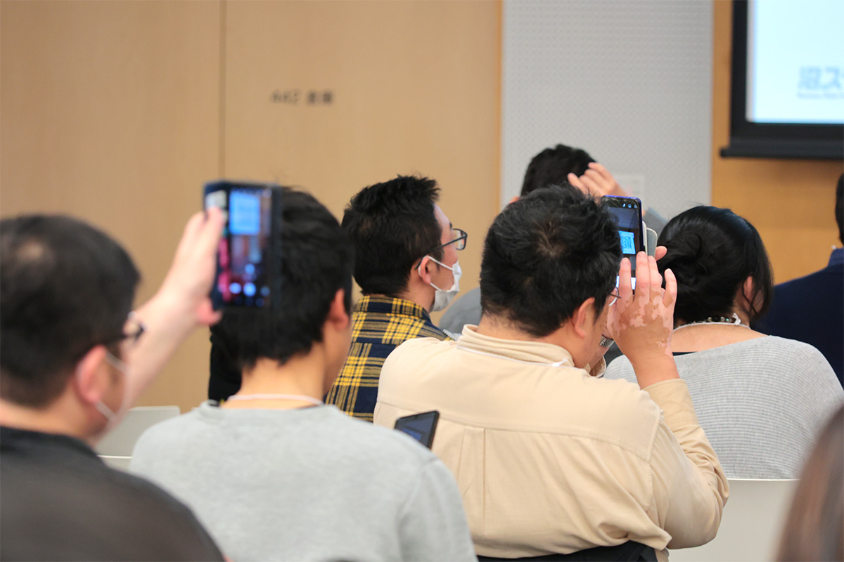 スクリーンに投影されたQRコードを撮影する聴衆